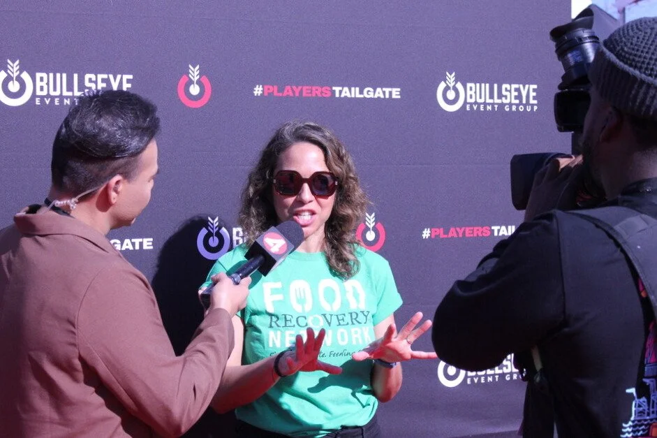 CEO Regina Harmon being interviewed at a Bullseye Event Group and Players Tailgate event, with a cameraman recording the interview.