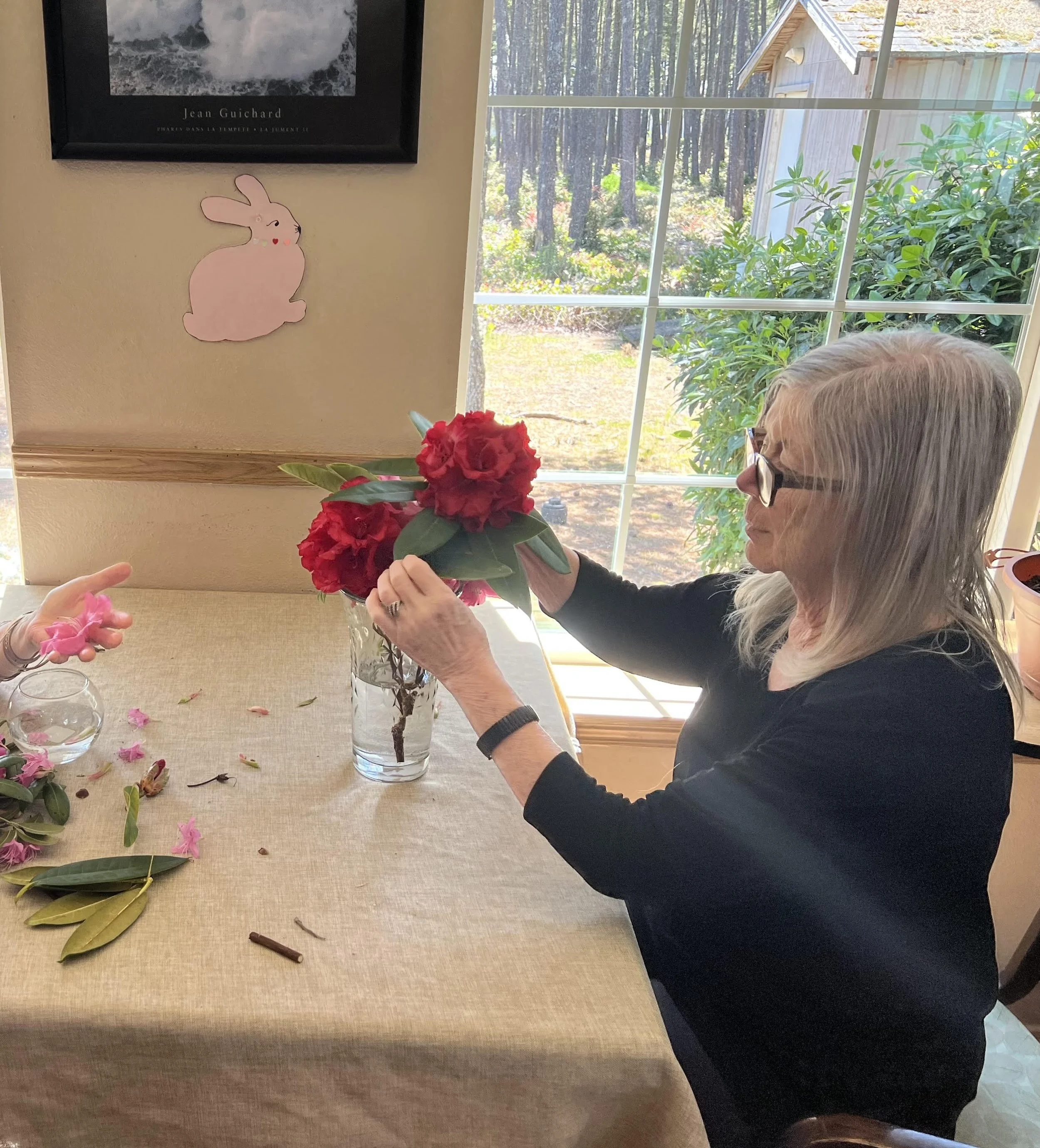 Woman in black arranging red rhododendrons