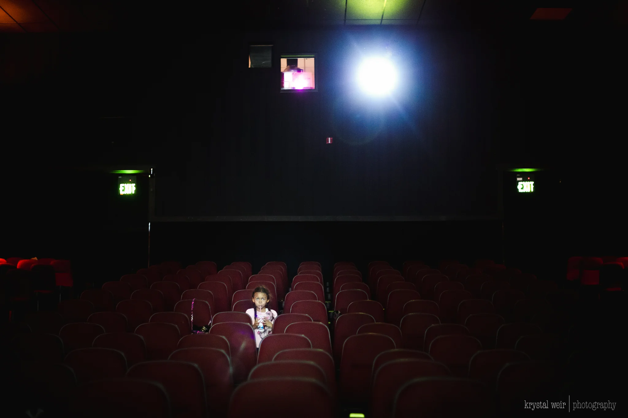 Day 17/365 When you arrive early and have the whole theater to yourself this is the shot you take! It is extremely hard to focus in a dark movie theater. Yes it's grainy/noisy, I had to up my ISO, nope she's not completely in focus, I did shoot this at a super slow shutter speed, but I got the shot and I love it as is. If you're wondering we saw the Trolls movie for the zillionth time! I always take my camera to the movies ever since I saw a photographer a couple of years ago take this gorgeous photo of her children at the movie theater. I've gotten plenty of theater shots, but most of them are the same shots. I kind of had a feeling today I would get a different, more eye catching shot. We went to a dollar theater on a Tuesday so I knew there may not be many people in the theater and we got there before they opened so I was correct. There was one person in the theater when we got in there so i took this opportunity to get a few shots of my daughter. It was pretty hard to get this shot because I was working with the light from the screen which was unpredictable, so trying to work fast was another issue. Focusing in a dark theater is also difficult task. I had to up my ISO pretty high in order to expose correctly for her face and that added grain/noise to the photo. Even though I used a high ISO my shutter speed was still very slow which didn't help my shaky hands which added to the face not be in complete focus. Although I had all these issues I really walked away being proud of what I did get and making it even better during the editing process. 