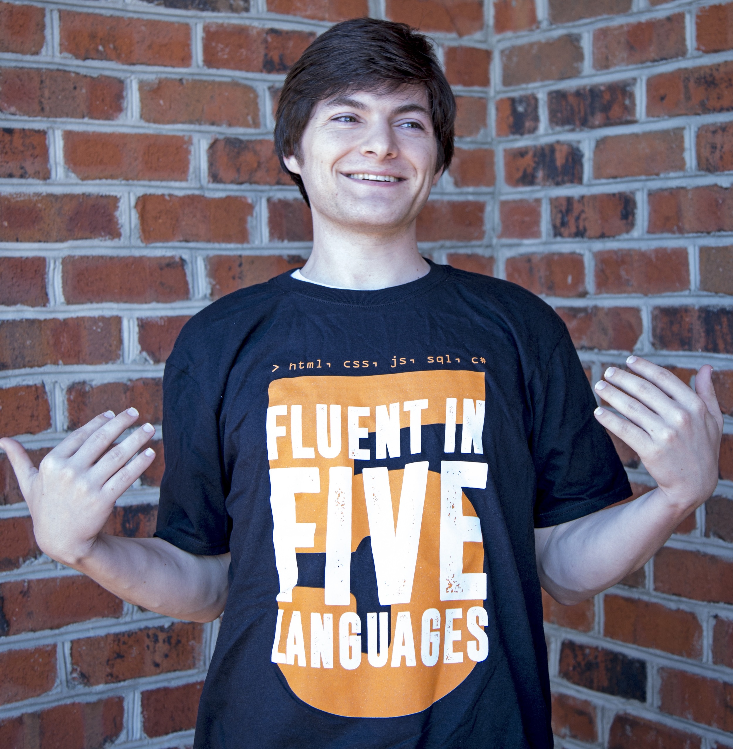 Coder Foundry graduate, Kenneth R. showing off his graduation T-shirt, "Fluent in 5 Languages"