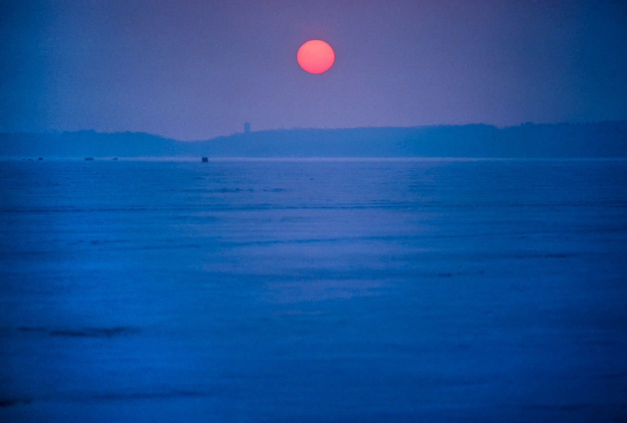 Orange Sun Setting Over Ice Fishing Shacks