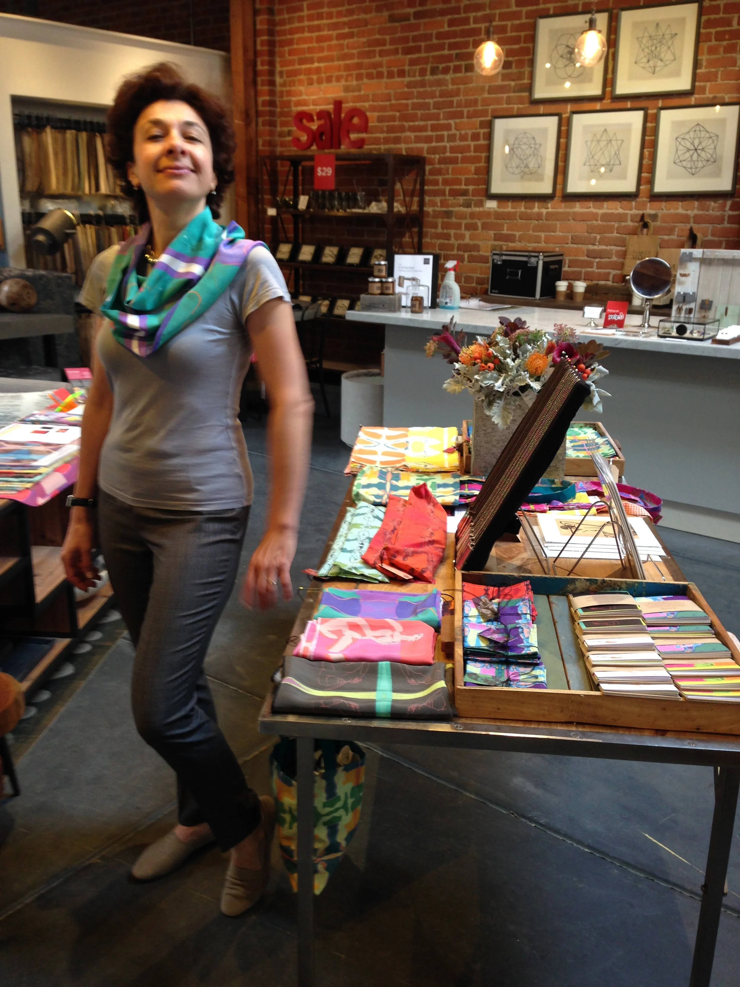 Valerie striking a pose in one of my art silk scarves. And check out the tables filled with my colorful. table linens, greeting cards, necklaces, gift wrap, tote bags, and more...