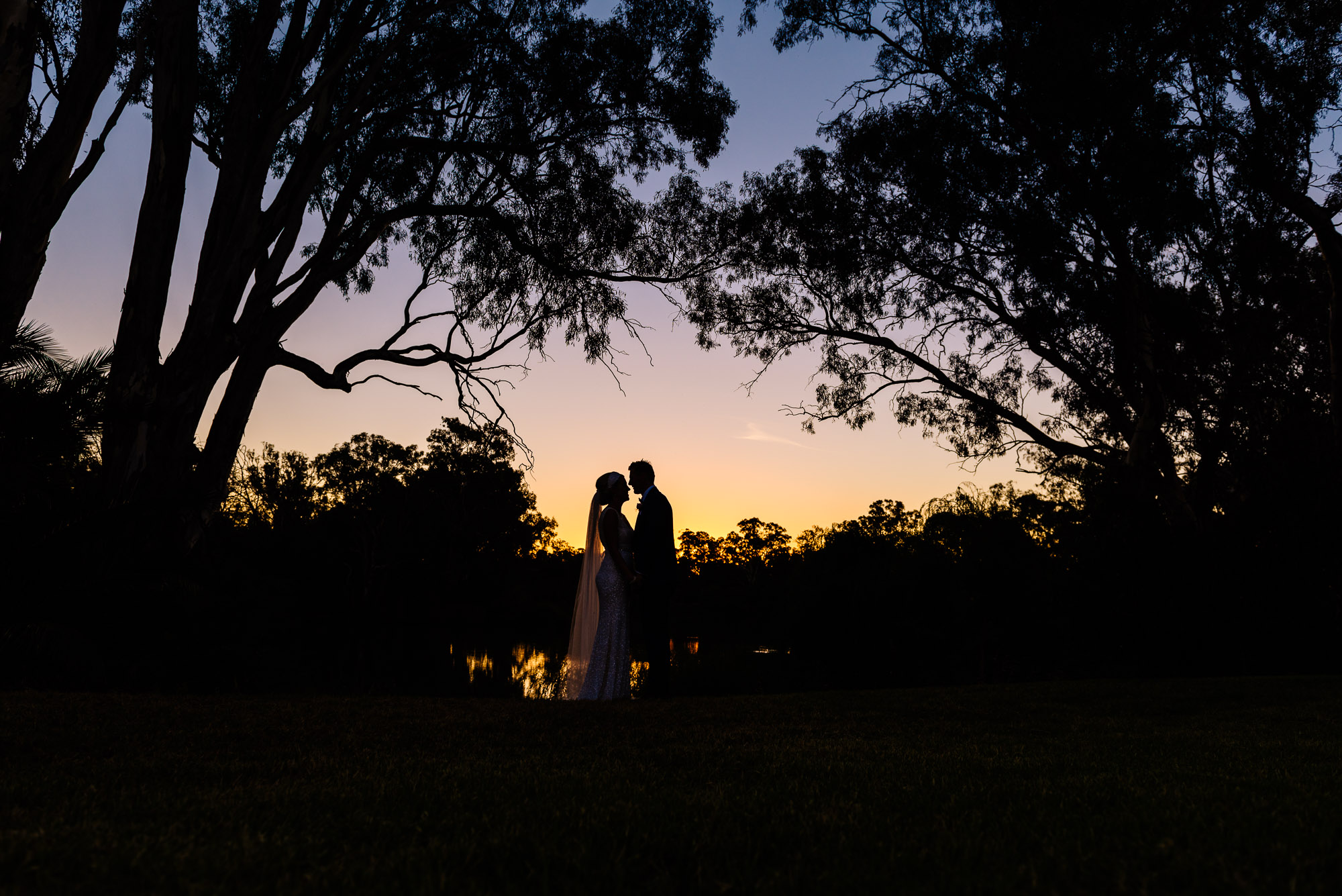 Sunset silhouette of the bride and groom by the river at Perricoota Station