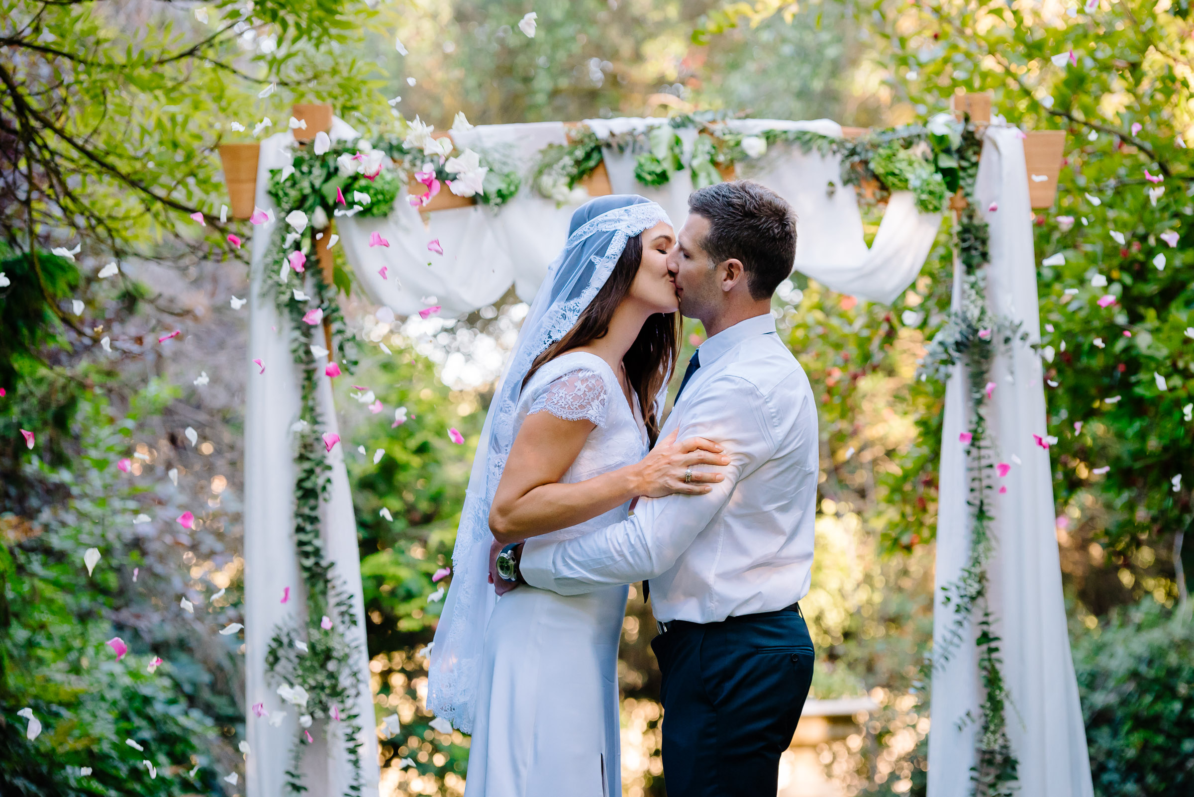 Carly and Daniel kissing in front of their amazing arbour