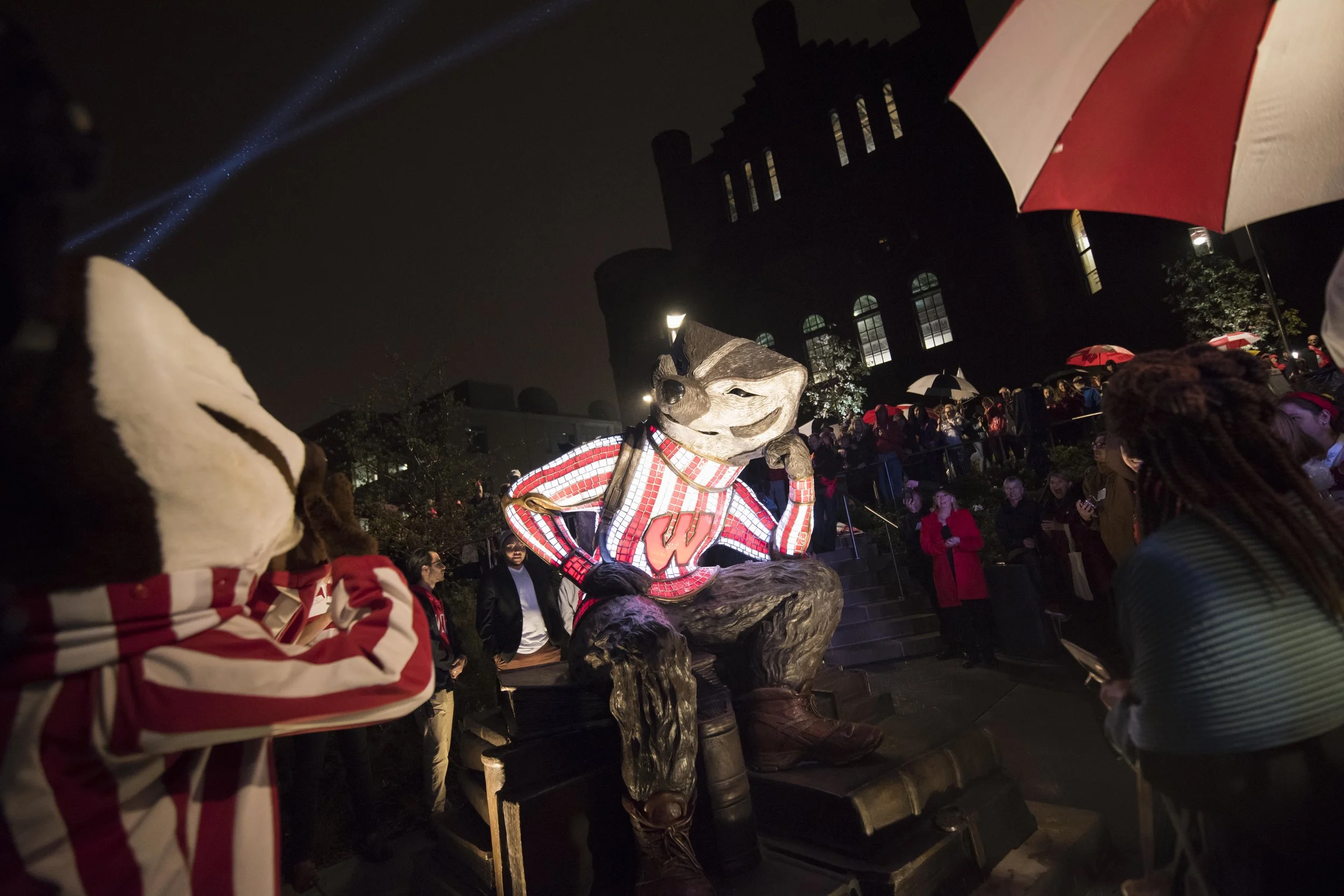 A blustery and rainy evening was the setting for the celebratory opening of the new lakefront Alumni Park at the University of Wisconsin, MadisonThe crowd was not hindered by the weather and with great fanfare they were enthusiastically greeted with the grand entrance of Bucky Badger, the well-loved scamp of a mascot, who arrived on a Harley Davidson motorcycle for the crowning moment they had all been waiting for - the unveiling of the sculpture of … Bucky himself! The sculpture of Bucky Badger, titled “Well Red” was uniquely created in bronze, stainless steel and stained glass (stained glass by artist Dan Neil Barnes) with the famous ‘W’ jersey illuminated. It was a great evening! The sculpture was well received by all! We are very thankful to have had the opportunity for such a fun and uplifting project. Go Badgers! https://www.alumnipark.com/exhibits/bucky-sculpture/