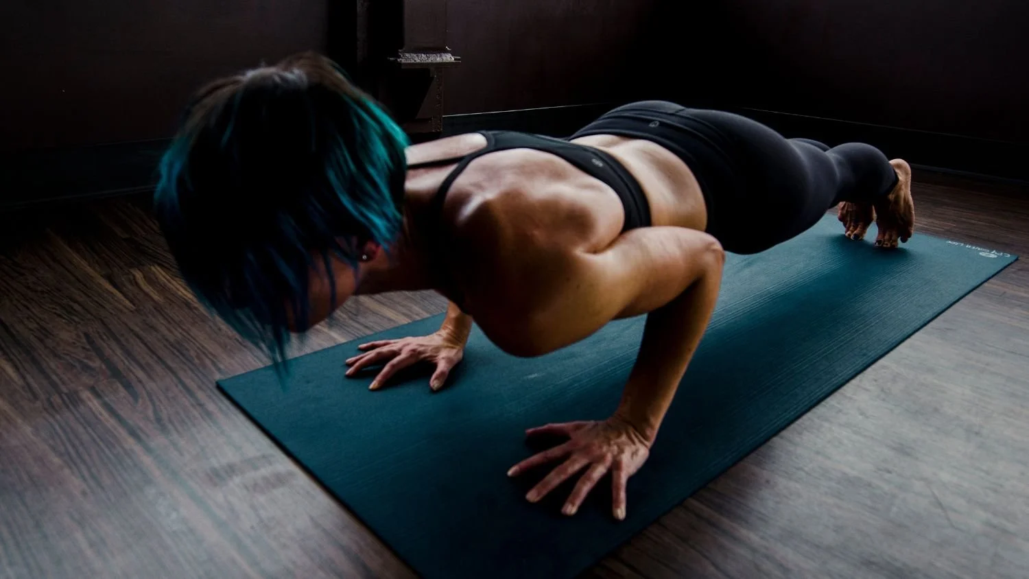 woman in a lowered down plank position on a blue yoga mat