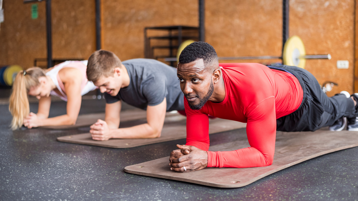 three people lined up in the plank position in a gym