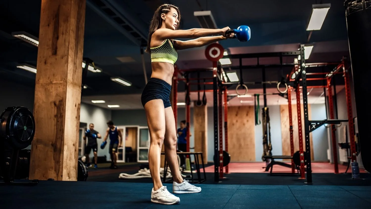 woman doing some kettlebell swings in a gym