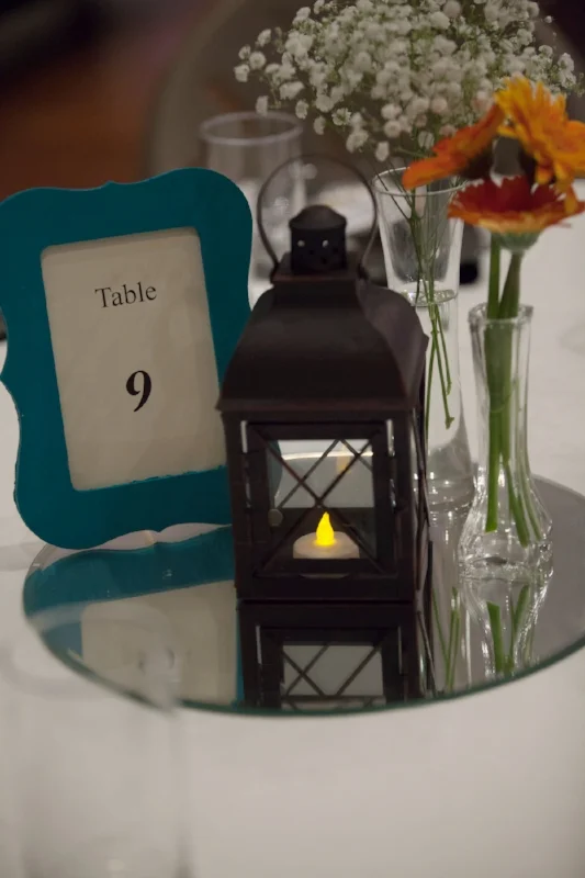 Lanterns used with frames and flowers on the table are a simple but beautiful option for table centerpieces