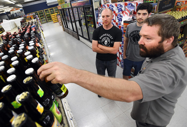 Kippie Loughlin, right, of Liquor Mart in Boulder, helps Michael Geramita, left, and Anthony Baraff, buy a 6-pack of assorted craft beers on Friday. (Cliff Grassmick Staff Photographer)