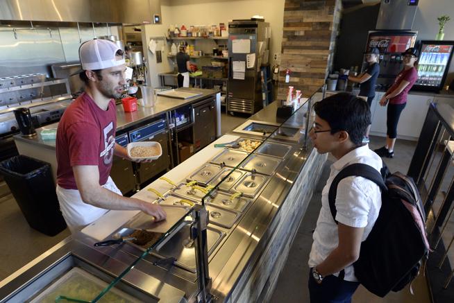 General Manager Taylor Graham works on a lunch order for Jorge Elizondo at Five on Black Brazilian Grill on Thursday in the 29th Street Mall. ( Jeremy Papasso / Staff Photographer )
