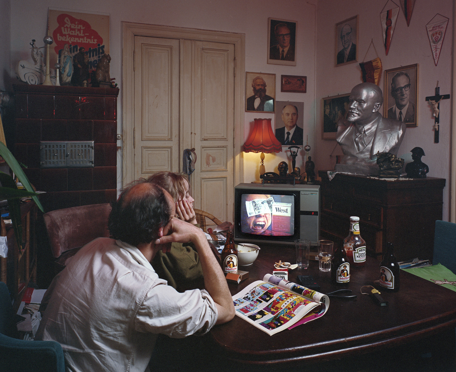 Of course, this is a set up. The montage on the television refers to the "Go wild west" slogan attached to the cigarette brand, the man with the money pasted to his forehead is an illustration from a magazine article discussing the economic changes taking place during the unification of the two German nations. There are many ways to look at the change, it could be thought of as a purchase of one economy by another as well as other things. The stuff on the wall is pretty well all east german nostalgica and kitsch put up for the shot. 1990 Berlin.
Normal
0
false
false
false
EN-CA
X-NONE
X-NONE
/* Style Definitions */
table.MsoNormalTable
{mso-style-name:"Table Normal";
mso-tstyle-rowband-size:0;
mso-tstyle-colband-size:0;
mso-style-noshow:yes;
mso-style-priority:99;
mso-style-parent:"";
mso-padding-alt:0cm 5.4pt 0cm 5.4pt;
mso-para-margin-top:0cm;
mso-para-margin-right:0cm;
mso-para-margin-bottom:8.0pt;
mso-para-margin-left:0cm;
line-height:107%;
mso-pagination:widow-orphan;
font-size:11.0pt;
font-family:"Calibri",sans-serif;
mso-ascii-font-family:Calibri;
mso-ascii-theme-font:minor-latin;
mso-hansi-font-family:Calibri;
mso-hansi-theme-font:minor-latin;
mso-fareast-language:EN-US;}
