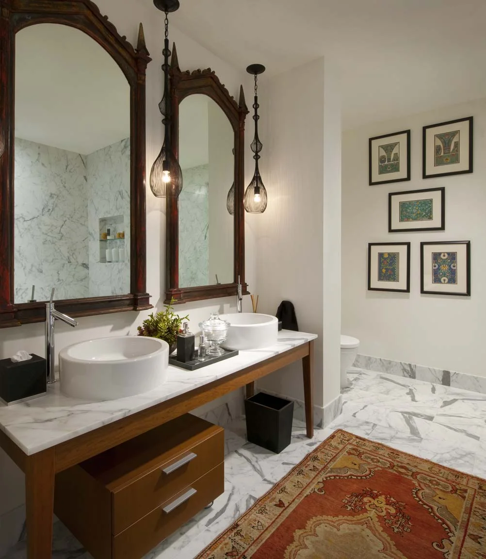 A traditional oriental rug can still belong in a contemporary setting if its colors and pattern complement the rest of the room. The mirrors in this bathroom are also inspired by Indian design.