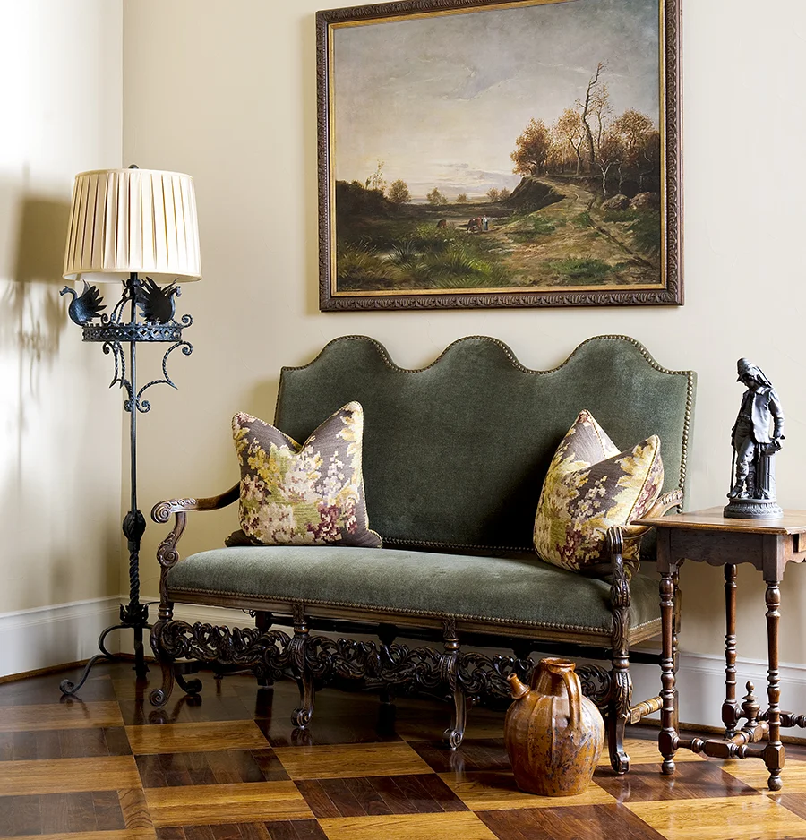 The checkered wood floor provides a striking geometric contrast to the ornate curved furniture over it in this French Country home.