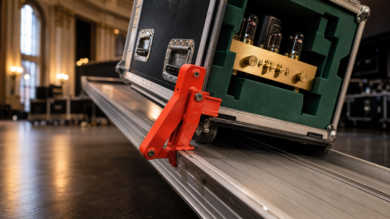 Flightcase met buizenversterker wordt op een laadbrug door een rode veiligheidsklauw tegengehouden