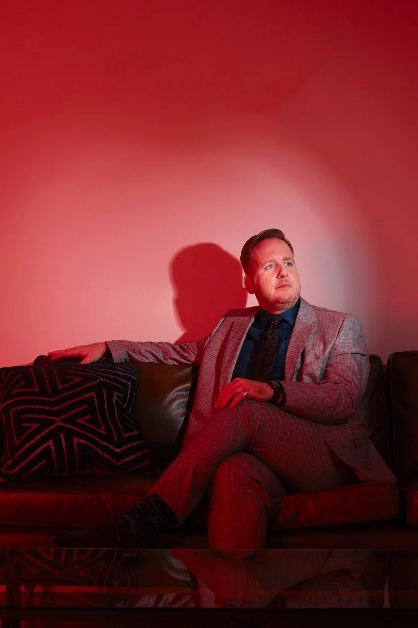 James Alan promo image thinking on couch with red light