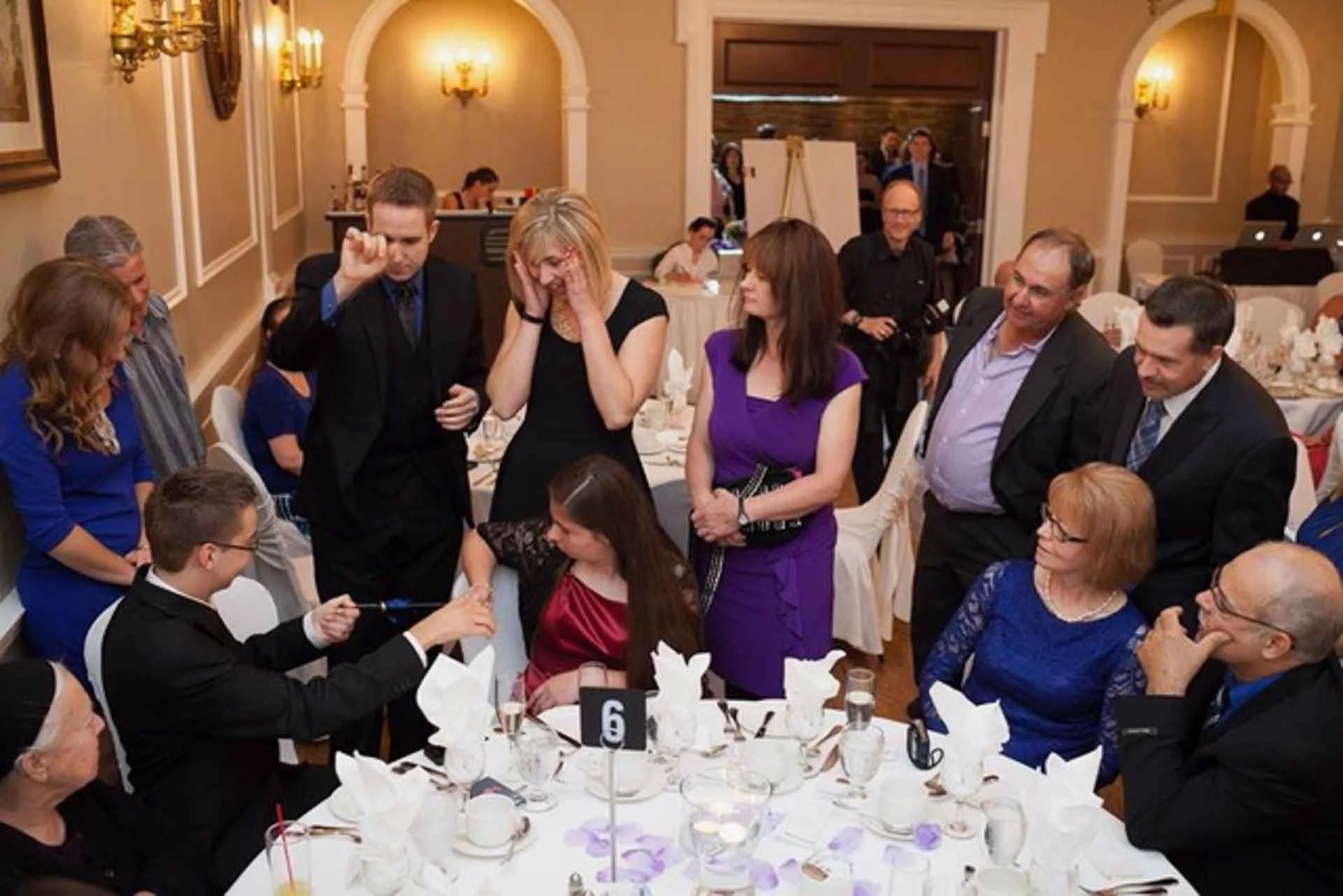 James Alan performing close up magic at a wedding banquet table surrounded by guests at the Old Mill in Toronto
