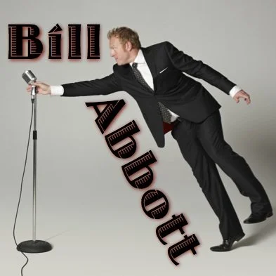 Bill Abbott reaching for old fashioned microphone on a stand