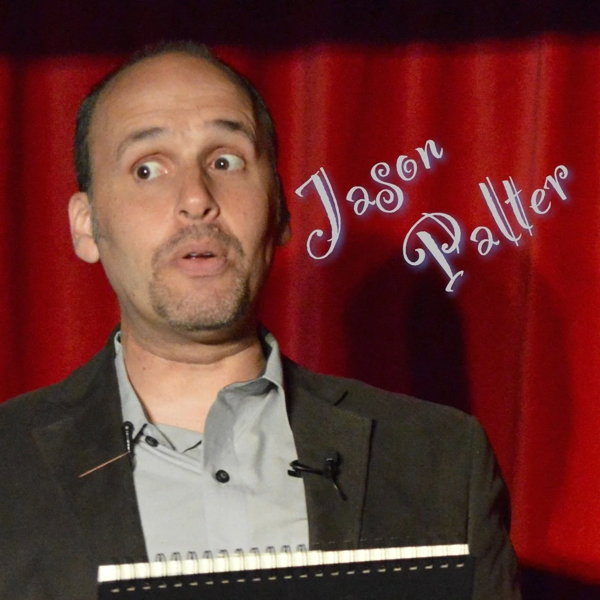 Jason Palter with a notepad surprised on stage at the Crimson Lounge
