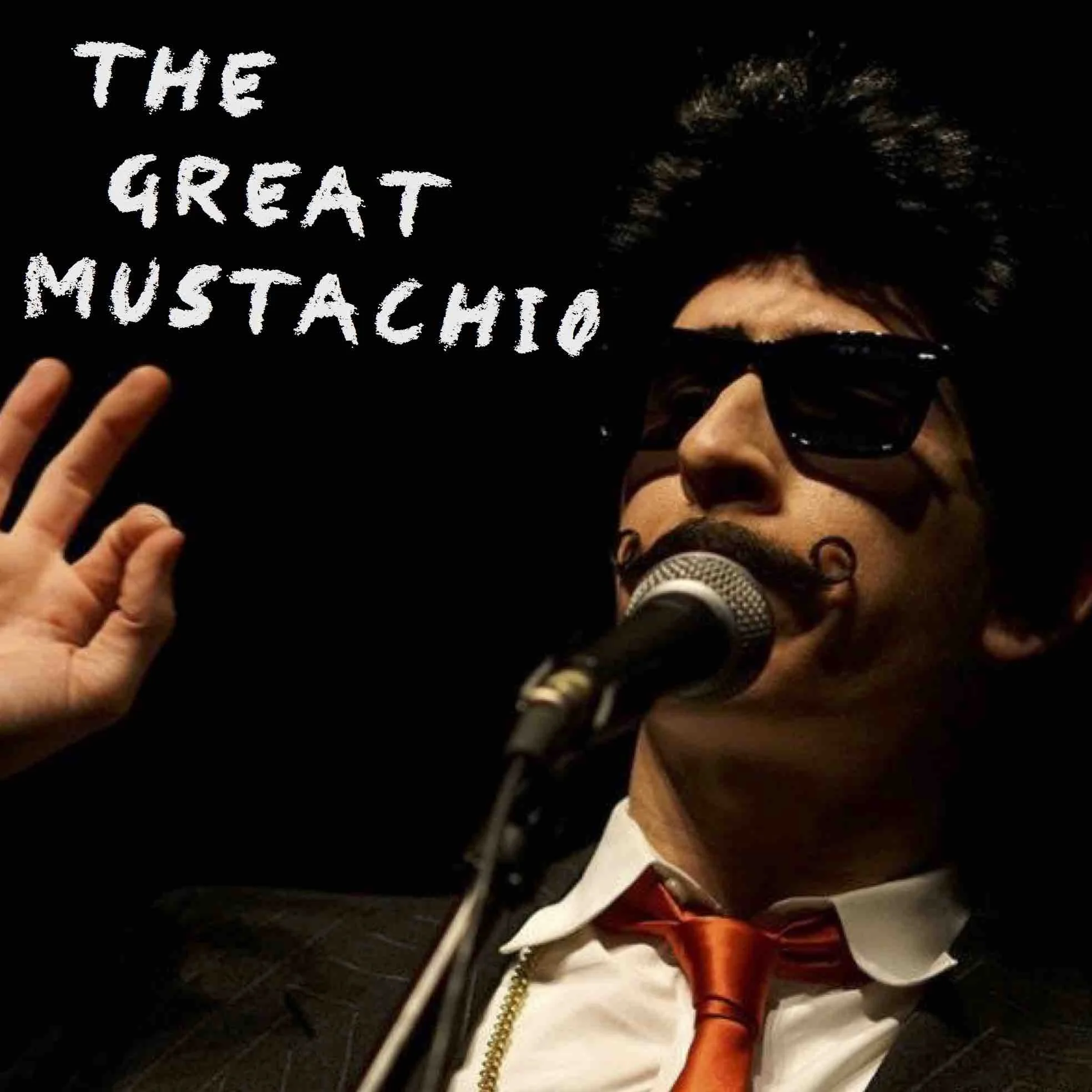 The Great Mustachio speaking into a mic on a stand