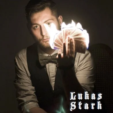 Lukas Stark promotional image holding a flaming fan of cards