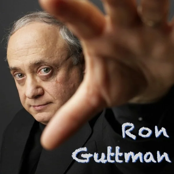 Ron Guttman headshot reaching towards the camera lens