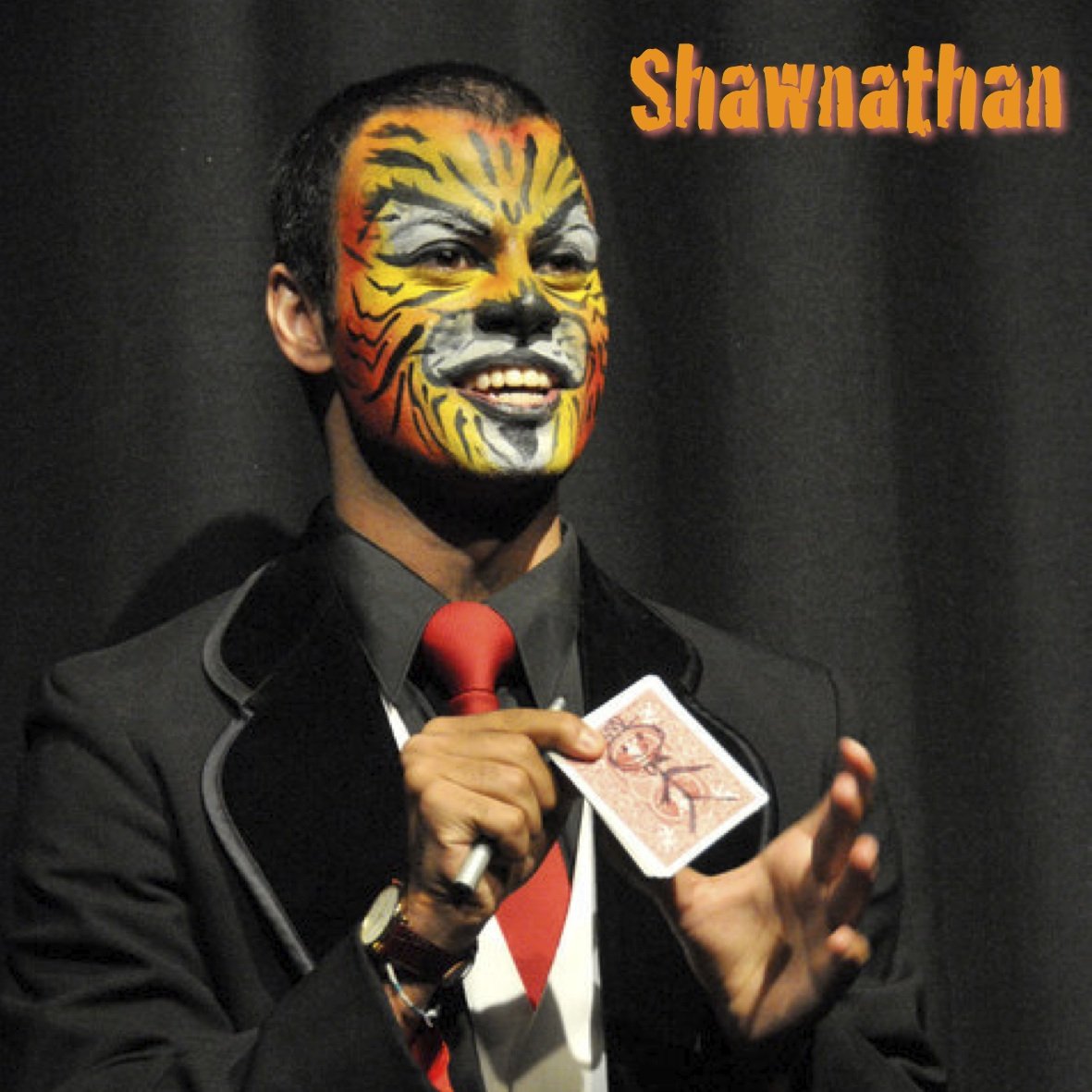 Shawnathan doing a card trick in full tiger facepaint