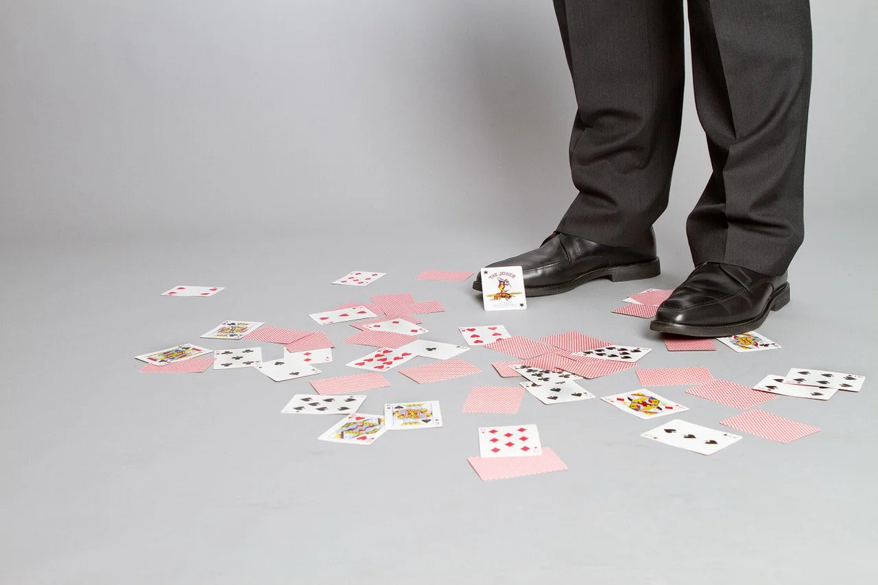 James Alan promo image playing cards scattered on the floor around James' feet with Joker front and center