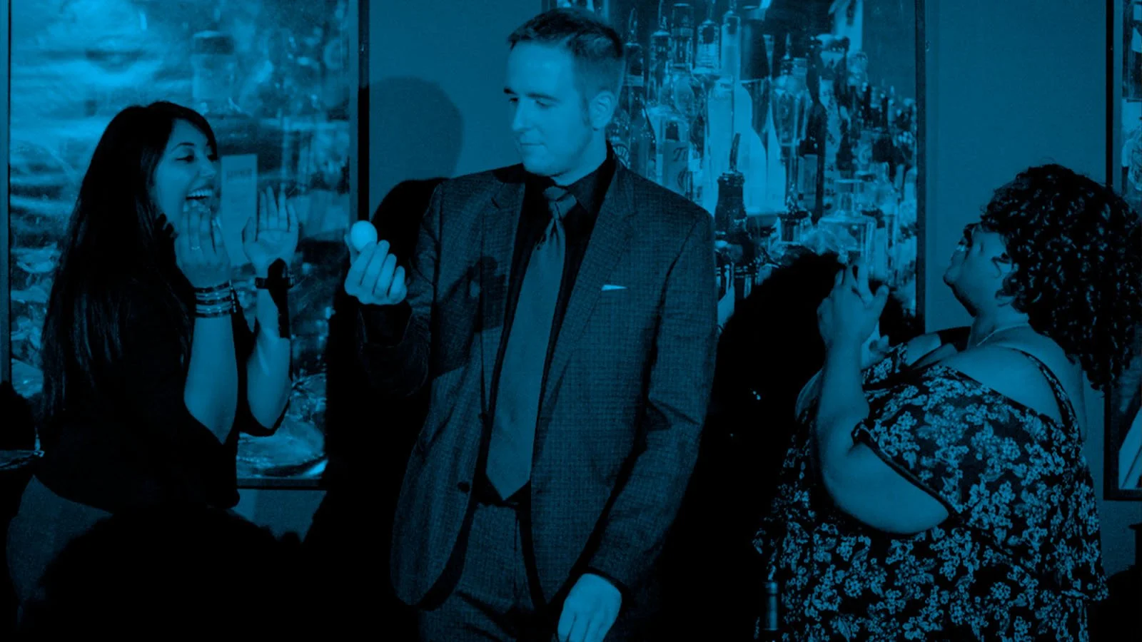 James Alan does magic with an egg for two smiling audience members at a private function in Toronto