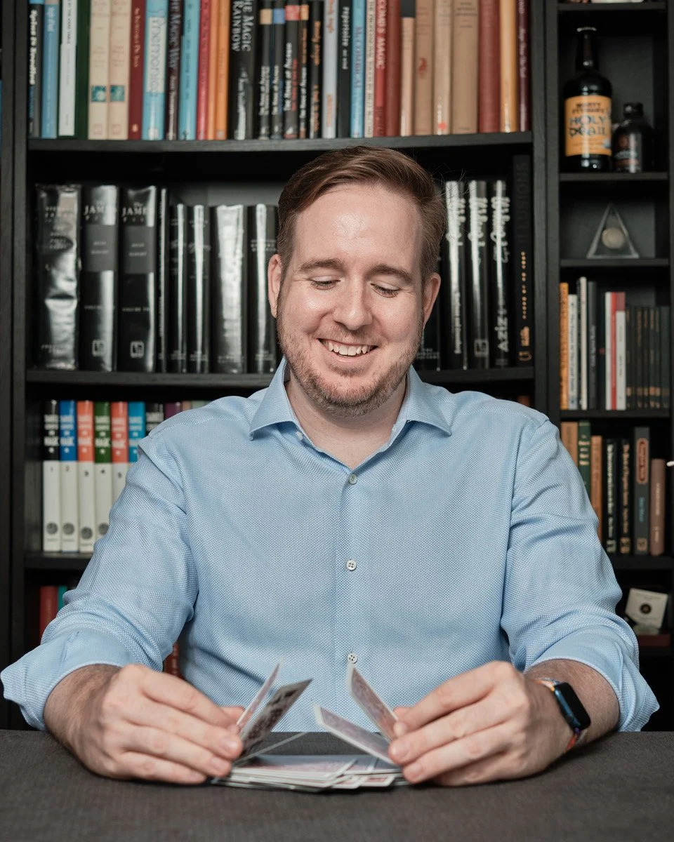 James Alan promo image shuffling cards in front of bookcase of magic books Toronto