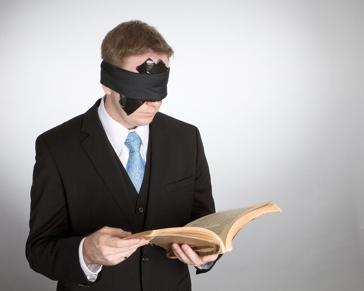 James Alan blindfolded with duct tape reading old book