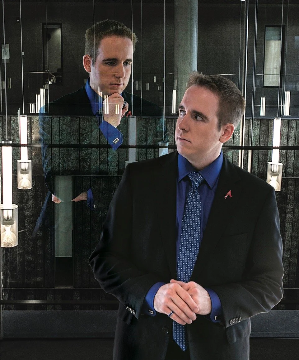 James Alan with a second James Alan looking over his shoulder from inside a reflection in a glass wall