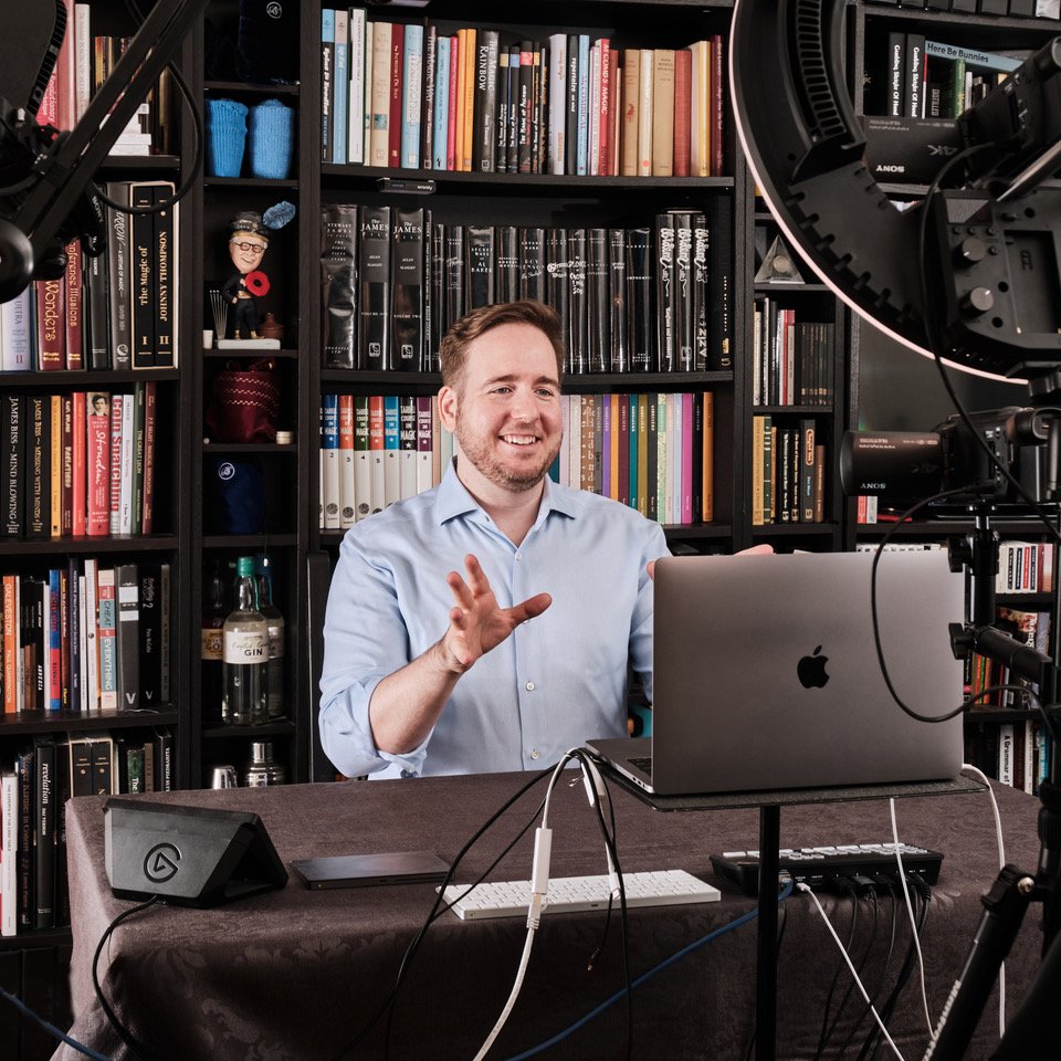 James Alan performing in his Toronto virtual studio with bookcase ringlight and laptop