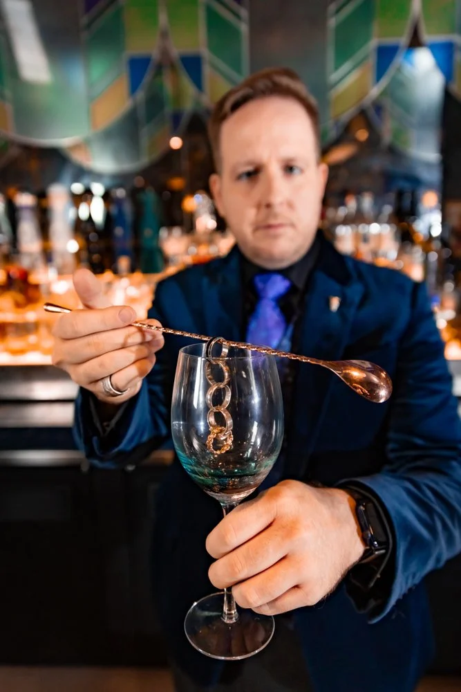 James Alan behind the bar at À Toi with finger rings magically linked in a chain