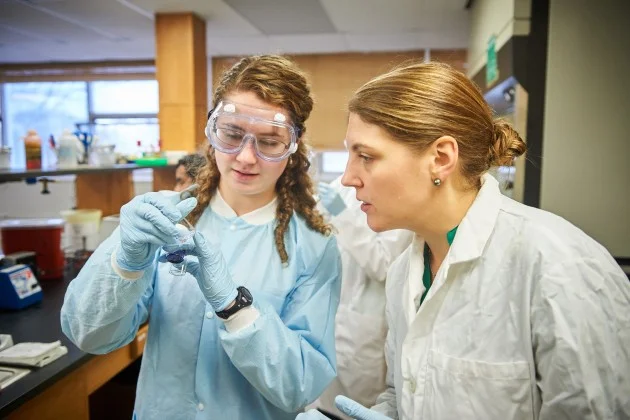 KATHERINE BELL '19 (CLAS), LEFT, AND NICHOLE BRODERICK – ASSISTANT PROFESSOR OF MOLECULAR AND CELL BIOLOGY – LOOK AT VIALS OF COLLECTED BACTERIA. (PETER MORENUS/UCONN PHOTO)