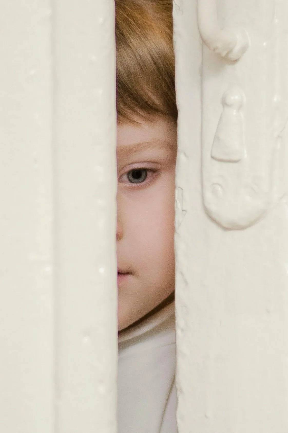 child peeking in door slit