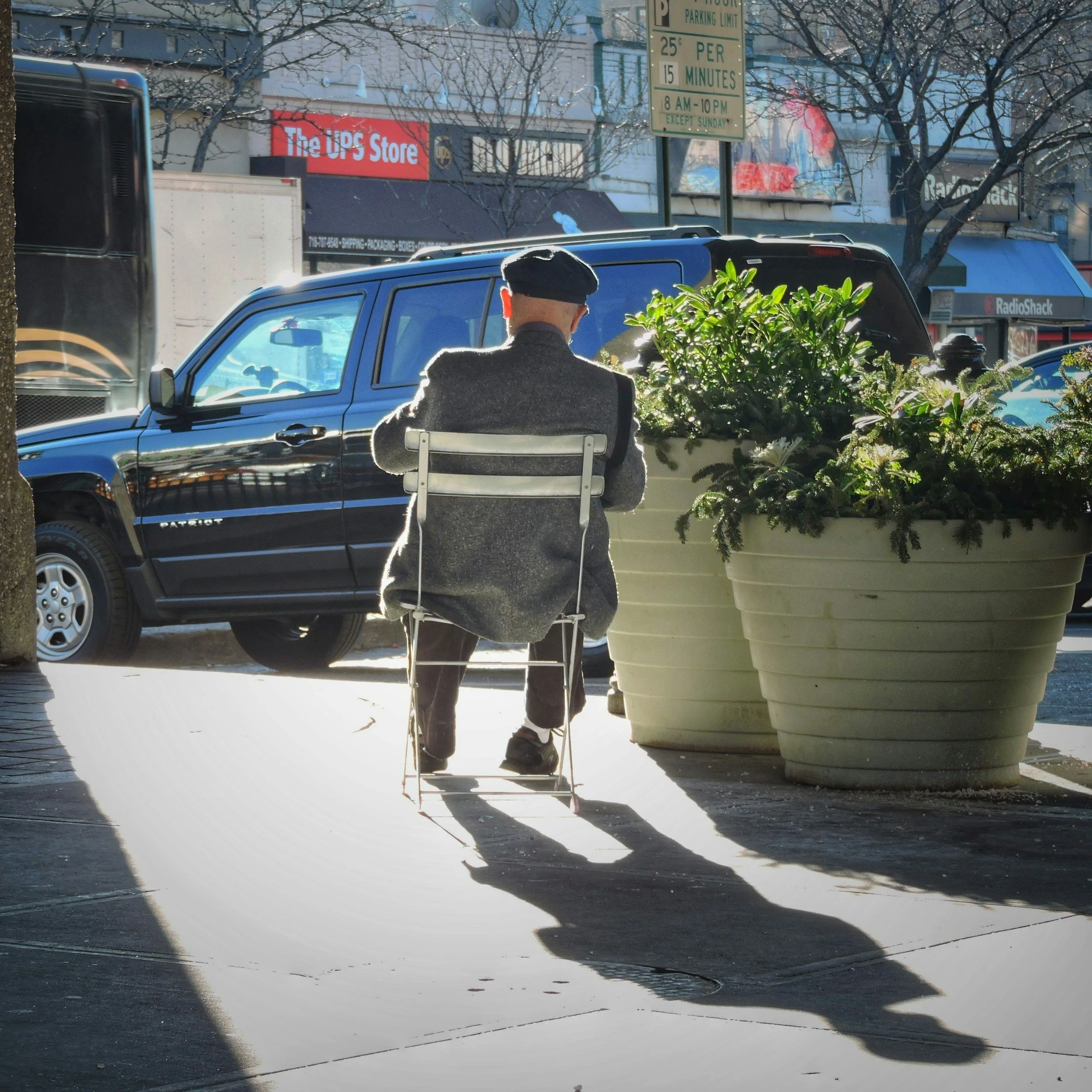 Man sitting in chair in a town enjoying the sun