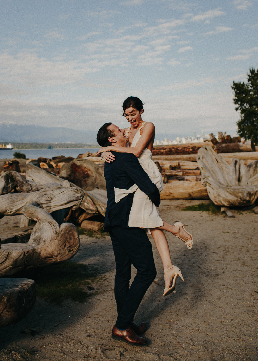 bride laughing as groom lifts her up