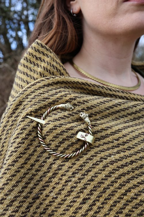 Viking style wool shawl with Celtic wolf-head brooch – Close-up of a handwoven medieval shawl fastened with a handcrafted brass and copper brooch, inspired by Viking and Norse designs