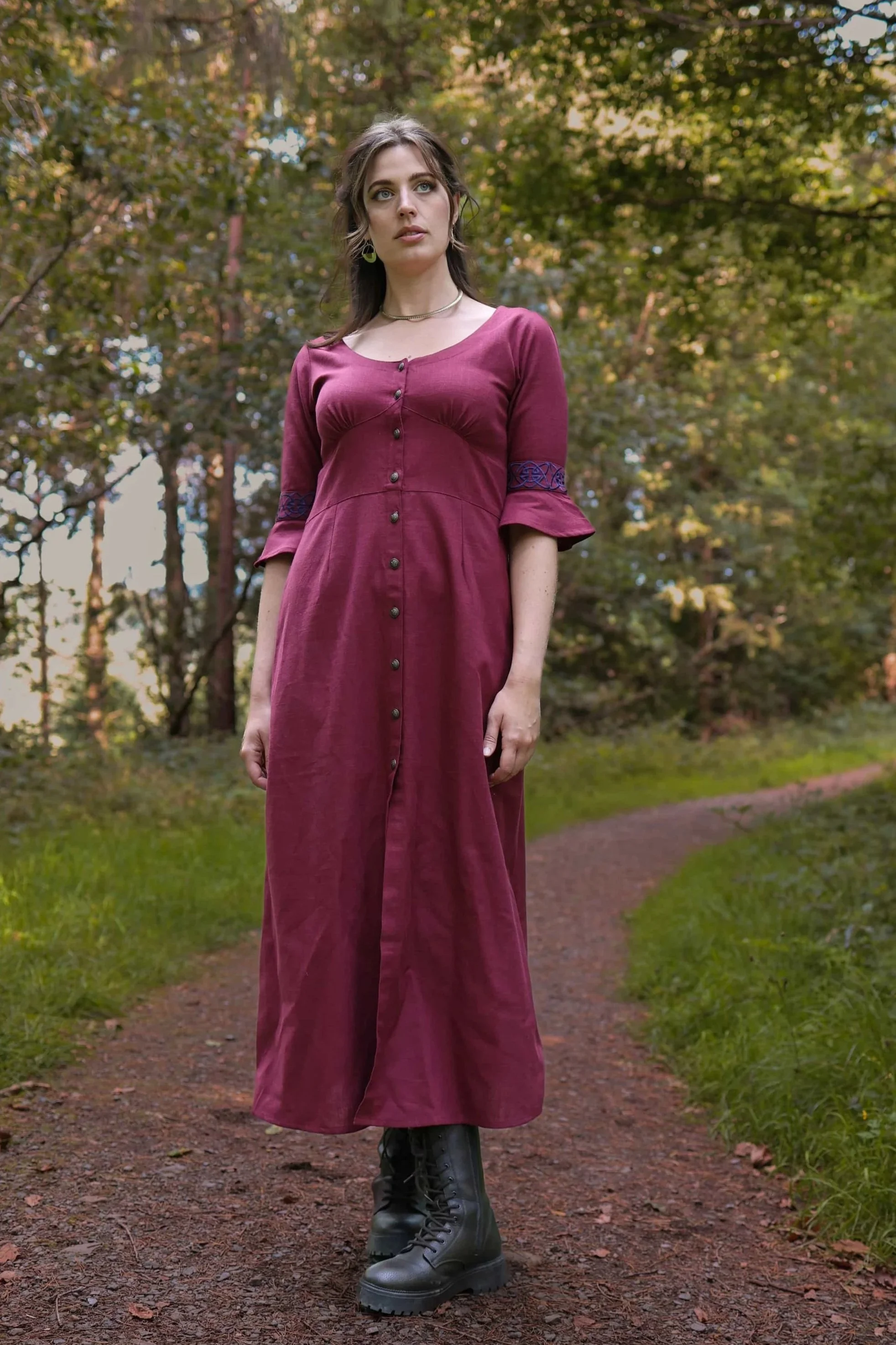 Model wearing a deep berry red Celtic dress with Celtic knot embroidery, button-down front, and flowing sleeves – Pooka Hawthorn Dress by Celtic Fusion Design