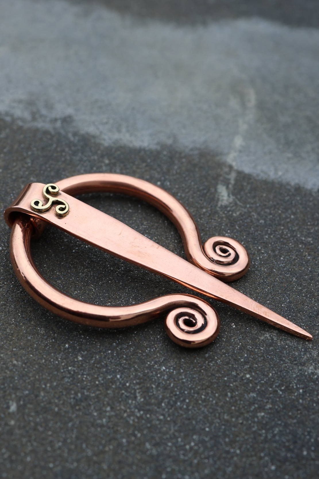 "Handcrafted copper Celtic shawl pin featuring elegant spiral detailing and a brass triskelion accent, inspired by traditional Irish design. Ideal for securing shawls or scarves