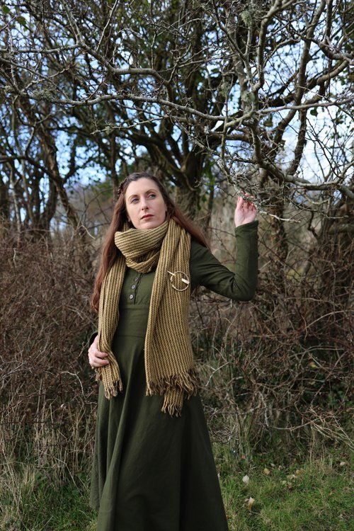 Handwoven Viking shawl with authentic Celtic brooch – Rustic outdoor shot of a model showcasing a traditional Norse wool shawl, accented with a detailed handcrafted Celtic brooch