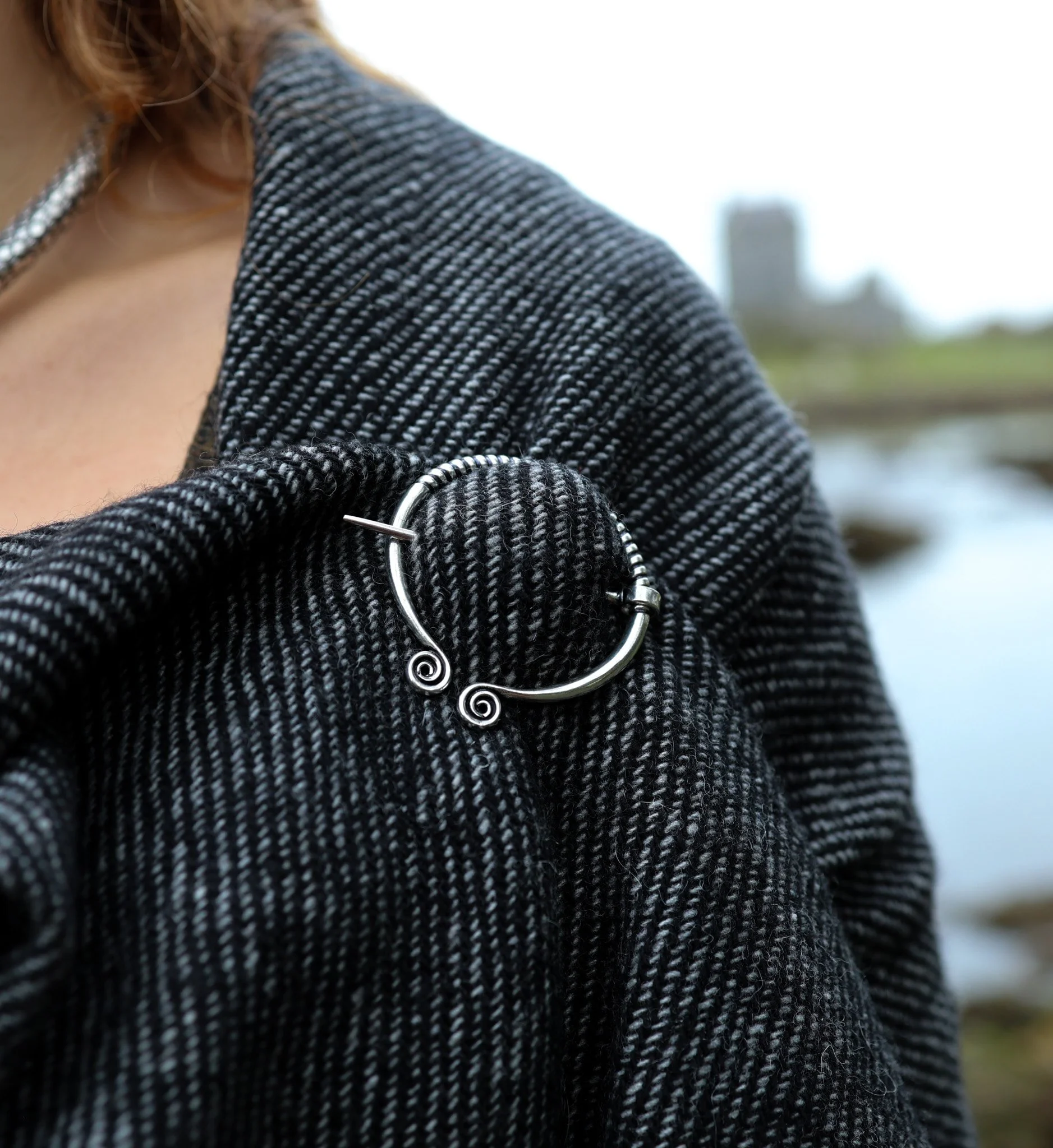 Celtic Spiral Shawl Brooch – silver-plated brass penannular brooch fastening a handwoven Irish shawl, inspired by ancient Celtic craftsmanship and folklore design.
