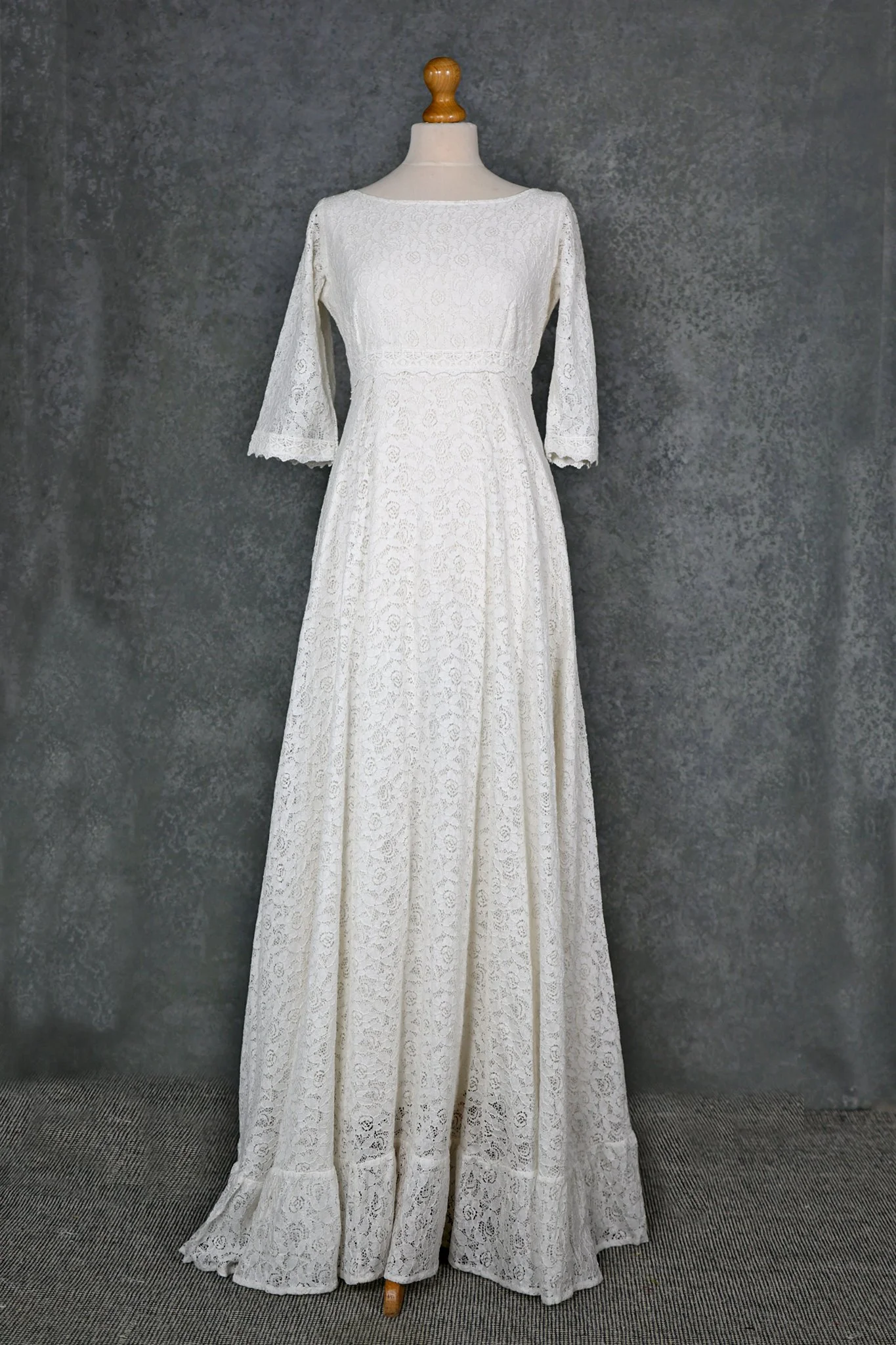 Willow Wedding Dress , a romantic Irish-designed gown made in soft ivory cotton lace, featuring a high neckline, V back, fluted sleeves, and a gathered frill hem