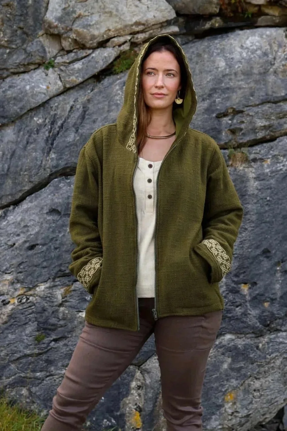 A woman wears the moss green Hooded Jacket with Fleece Lining and Embroidered Celtic Knotwork