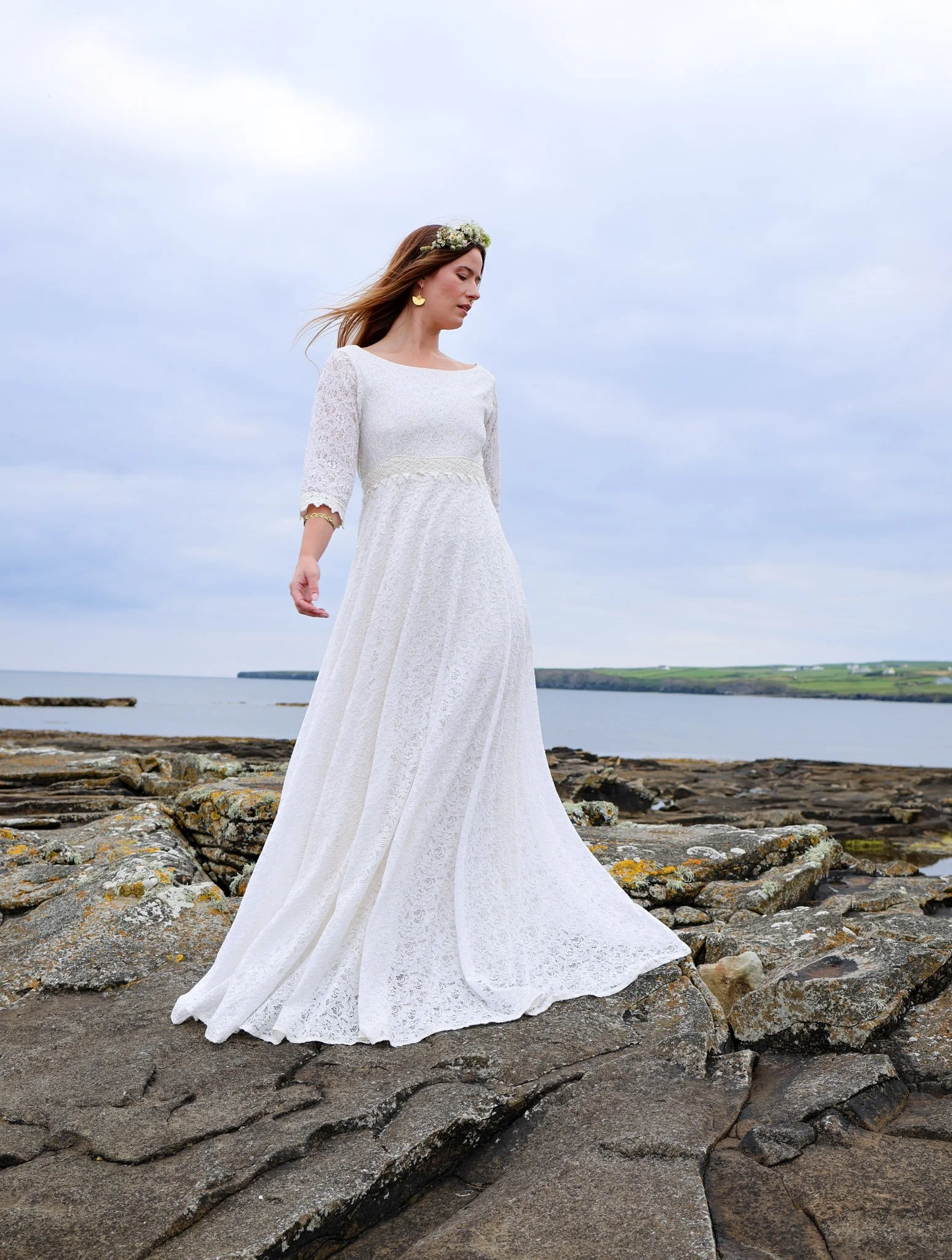 Willow Wedding Dress , a romantic Irish-designed gown made in soft ivory cotton lace, featuring a high neckline, V back, fluted sleeves, and a gathered frill hem