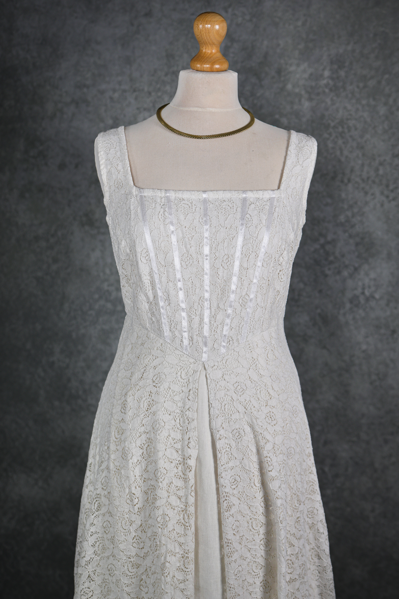 The Lir Wedding Dress, a Celtic-inspired Irish bridal gown featuring ivory lace over linen, a ribboned corset bodice, and detachable sheer sleeves tied with tassels for romantic styling options.