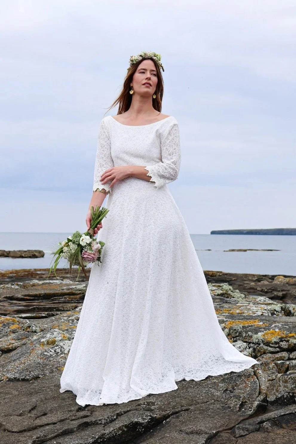 Willow Wedding Dress , a romantic Irish-designed gown made in soft ivory cotton lace, featuring a high neckline, V back, fluted sleeves, and a gathered frill hem