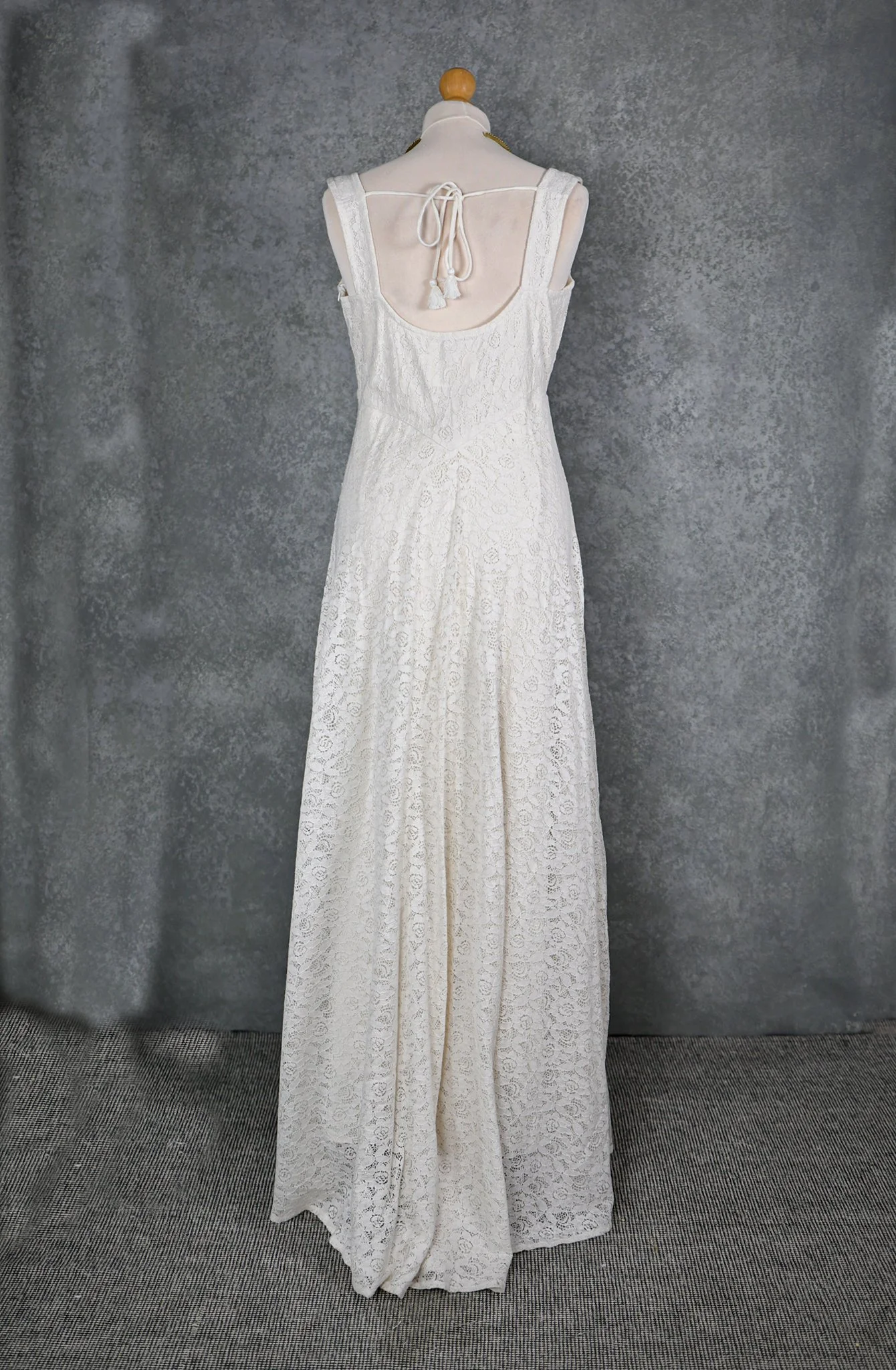 The Lir Wedding Dress, a Celtic-inspired Irish bridal gown featuring ivory lace over linen, a ribboned corset bodice, and detachable sheer sleeves tied with tassels for romantic styling options.
