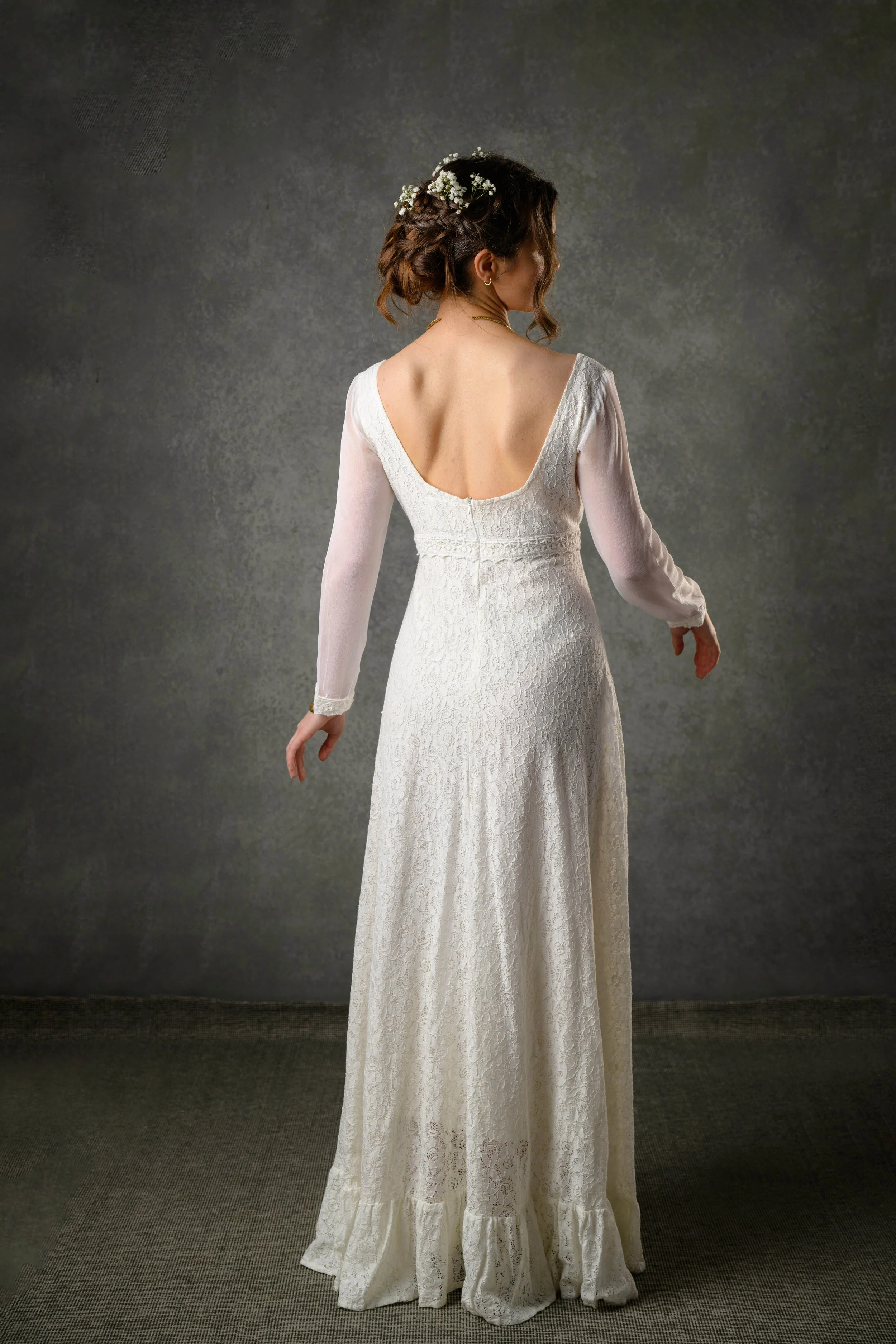 Regency style cotton lace wedding dress with bishop chiffon sleeves and a low scoop back. Features delicate waist lace trim and a ruffled hem.